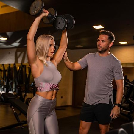 Five Jumeirah Village Дубай Экстерьер фото Personal trainer assisting a woman with a dumbbell press